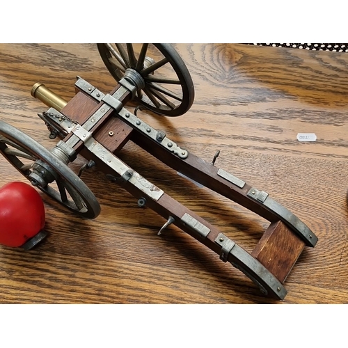 444 - A heavy vintage brass and wood miniature cannon on wheels, measuring approximately 15 inches in leng... 