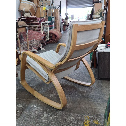 496 - A sleek and stylish oak rocking chair with light grey cushioned seat and backrest. Approximately 100... 