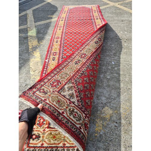 693 - Star Lot: A beautiful long hand knotted, Indian made, runner rug. A vibrant piece, predominantly in ... 