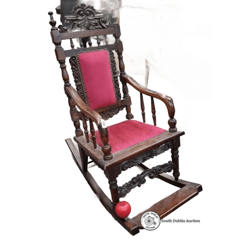 623 - A vintage colonial style rocking chair with velvet upholstery and intricate carvings to frame.