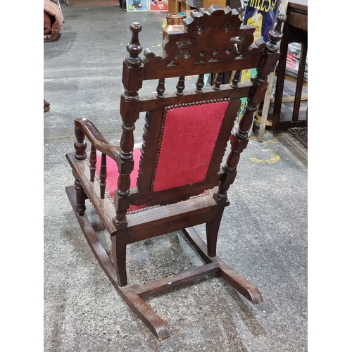 623 - A vintage colonial style rocking chair with velvet upholstery and intricate carvings to frame.