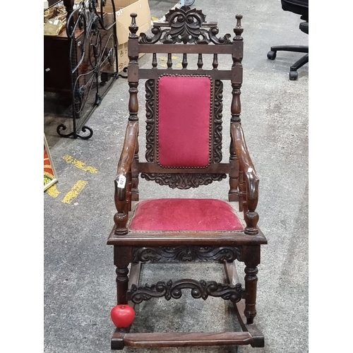 623 - A vintage colonial style rocking chair with velvet upholstery and intricate carvings to frame.