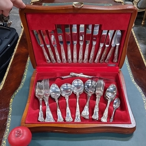 634 - A newbridge Stainless steel cutlery set consisting of knives, forks, and spoons, housed in a red vel... 