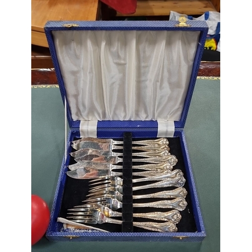 636 - Set of 12 silver-plated fish forks and knives in ornate design, presented in a blue case.