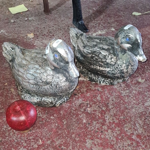 862 - Pair of stone  duck sculptures with textured feather detail and painted eyes. Approximately 10 inche... 