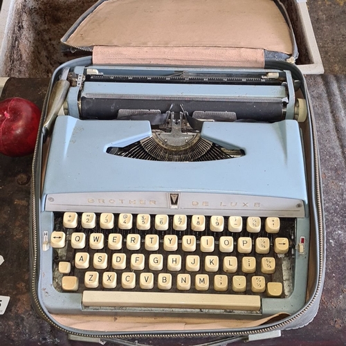 873 - Vintage Brother De Luxe typewriter in a carry case, featuring cream keys and a pale blue body.