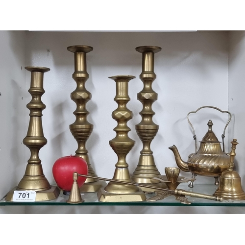 701 - A selection of solid brass items including four tall candlesticks, a bell, and a teapot.