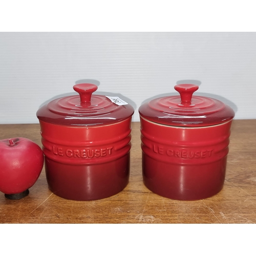 769 - A pair of Le Creuset lidded storage jars in the iconic cerise red colour. Both in good condition.