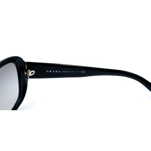 21 - A pair of original designer Prada sunglasses 'Made in Italy' with serial marks to frame. Lenses in g... 