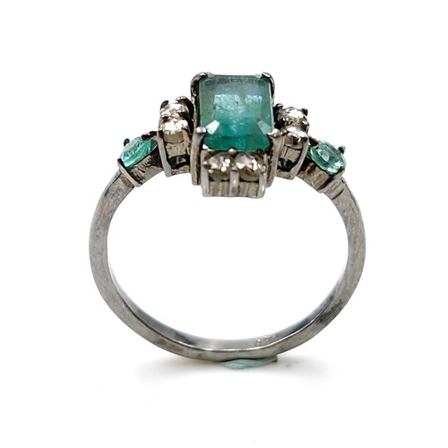 520 - Star Lot : A very pretty  three emerald and eight diamond ring mounted in sterling silver. Size - P.... 