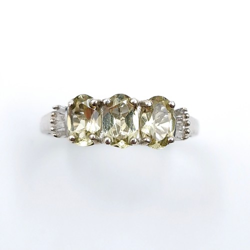 560 - A most attractive three stone peridot ring with diamond accents to shoulders set in sterling silver.... 