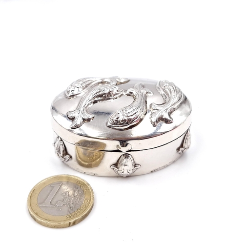 19 - A pretty white metal pill box set with hinged and embossed lid featuring fish. Dimensions - 5.5 x 2.... 