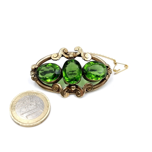 433 - An antique three stone peridot brooch set in pinch beck. Dimensions: 5 x 3 cms. Weight - 10 grams. S... 