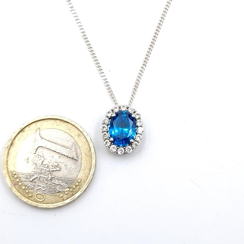 481 - A blue topaz pendant with cubic zirconia surround set with silver chain. Length - 46 cms. Boxed.