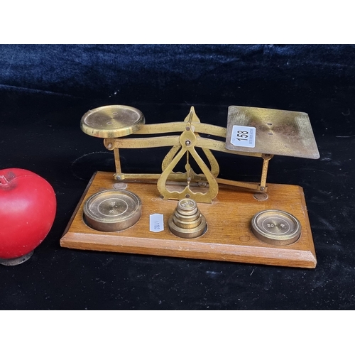 158 - A vintage desktop brass scales mounted on to a wooden plinth base with six brass weight in total. Ma... 