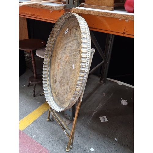 648 - Antique brass folding tray table with scalloped edge detail. Approximately 25 inches tall by 18 inch... 