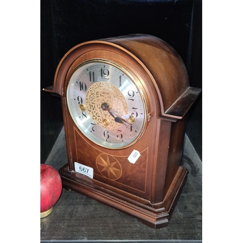 667 - A Franz Hermle Mahogany mantel clock with brass mechanism and decorative face, marked 