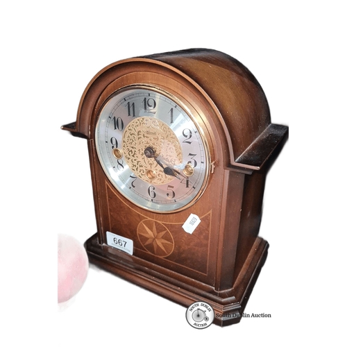 667 - A Franz Hermle Mahogany mantel clock with brass mechanism and decorative face, marked 