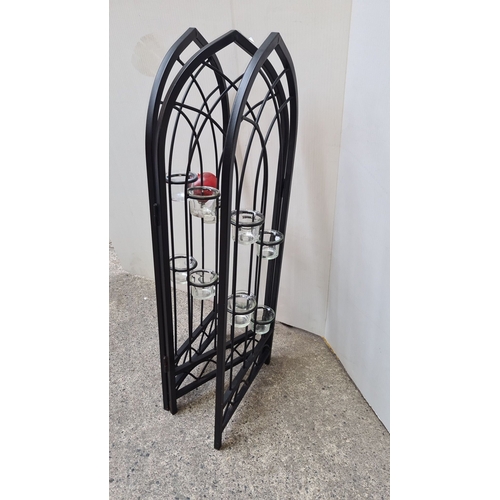 699 - Black wrought iron folding candle holder with Gothic arches design, featuring eight glass candle cup... 