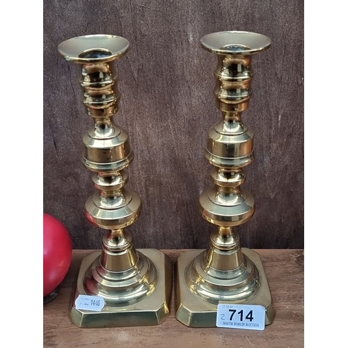 714 - Pair of brass candlesticks, approximately 10 inches tall, featuring a classic turned design with squ... 