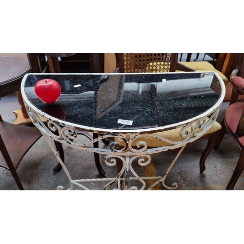 777 - Wrought iron and black glass demi-lune console table with decorative scrollwork. Approximately 75 cm... 