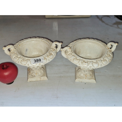 380 - A pair of neatly sized heavy cast metal garden urns in a white finish.