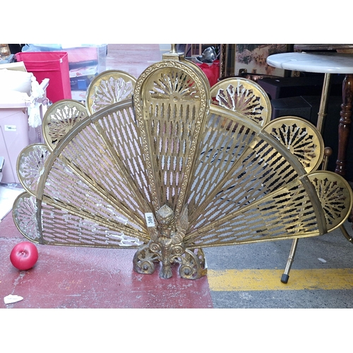 386 - A fabulous early 20th century peacock fan fire guard. Designed in brass with a pierced filigree styl... 