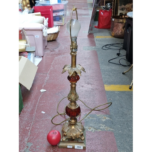 392 - An elaborate Hollywood Regency style painted brass table lamp with amber glass and brass fittings.