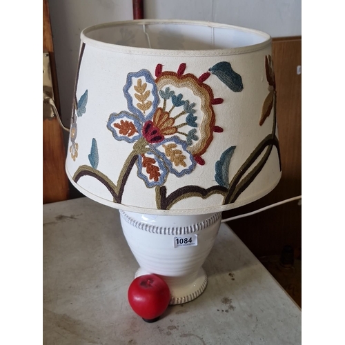 1084 - White ceramic table lamp with embroidered floral fabric shade. Approximately 14 inches tall.