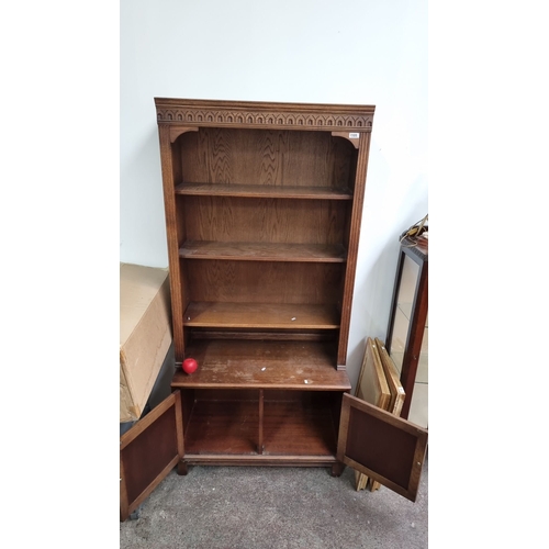 1105 - Antique oak bookcase with Gothic Revival details, three open shelves, and two lower cabinet doors. A... 