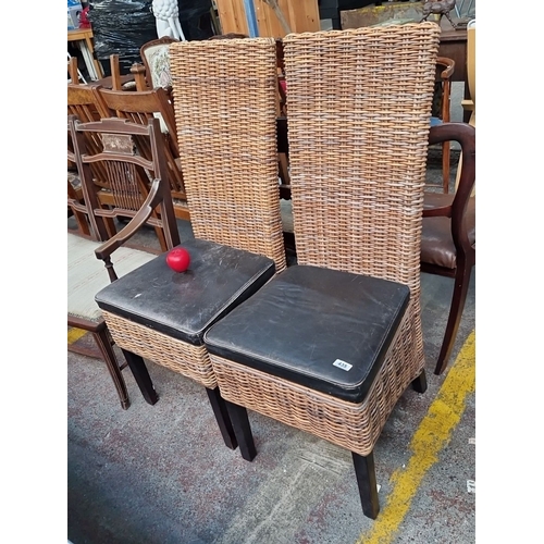 1294 - Pair of wicker chairs with high backs and black leather cushions. Dimensions: 100 cm high, 40 cm sea... 