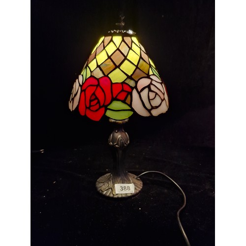 388 - A neatly sized Tiffany style table lamp featuring rose like motifs in rich deep tones with light pin... 