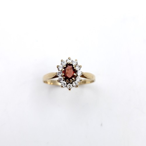 1122 - A lovey garnet stone ring with gem set cluster surround set in nine carat gold (375). Ring size - O.... 