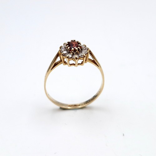 1122 - A lovey garnet stone ring with gem set cluster surround set in nine carat gold (375). Ring size - O.... 