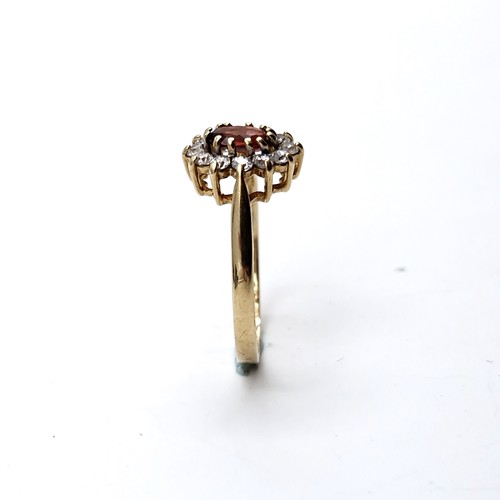 1122 - A lovey garnet stone ring with gem set cluster surround set in nine carat gold (375). Ring size - O.... 