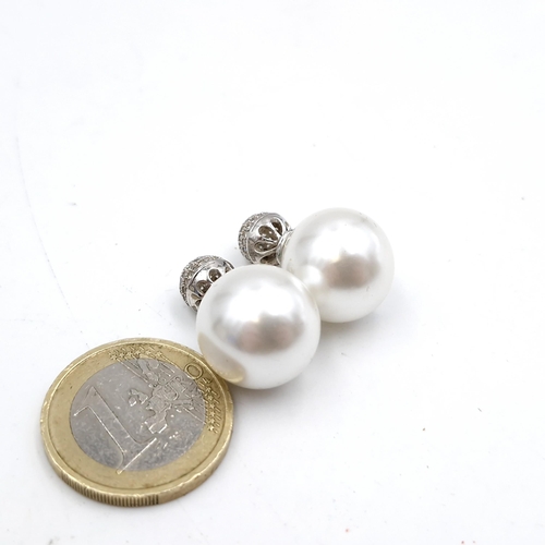 55 - A pair of large luster pearl stud earrings with gem set detailing to backs. Pearls 1.5mm diameter. W... 