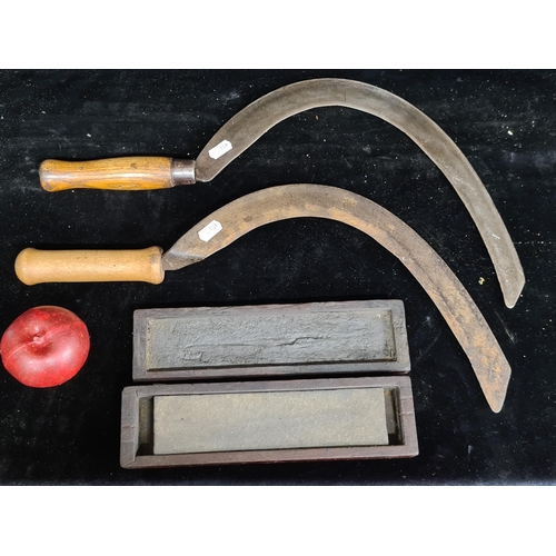 115 - Three antique items including two stamped sickles and a sharpening stone.