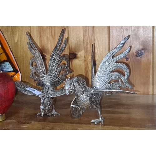 696 - Pair of metal rooster sculptures, showcasing dynamic poses and elaborate plumage.