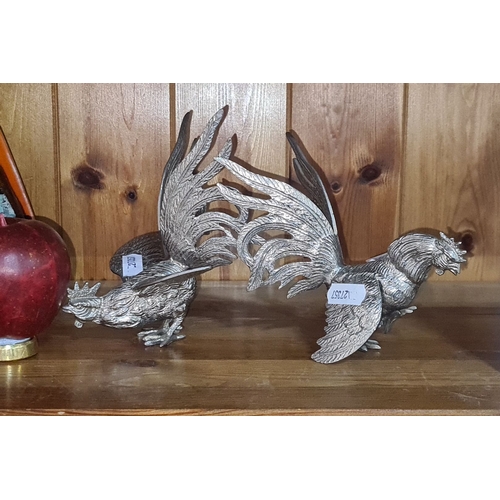 696 - Pair of metal rooster sculptures, showcasing dynamic poses and elaborate plumage.