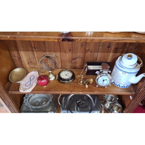 711 - Mixed lot featuring brass sundial, red , decorative teapot, metal clocks, and glass-topped jar. Ecle... 