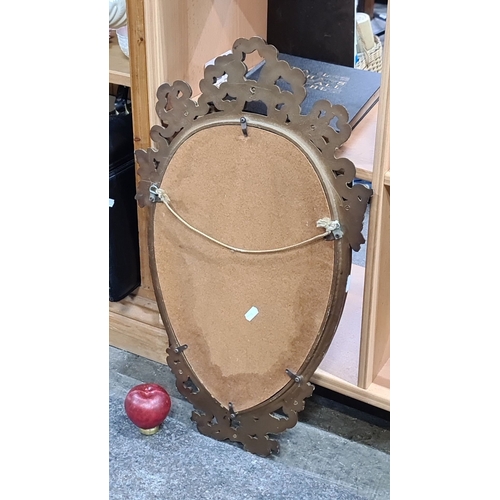 734 - Gilt-framed oval mirror, featuring intricate floral motifs, from the Victorian era.