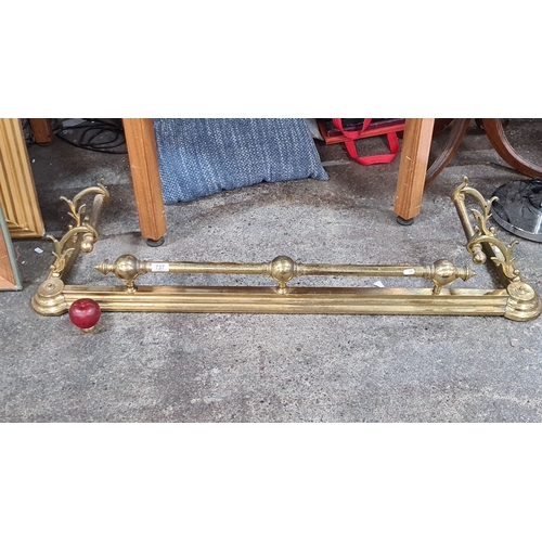 737 - Victorian brass fire fender with ornate scrollwork and polished finish, featuring turned finials and... 