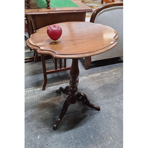 752 - Mahogany pedestal wine table features a scalloped edge top and intricately carved tripod base.