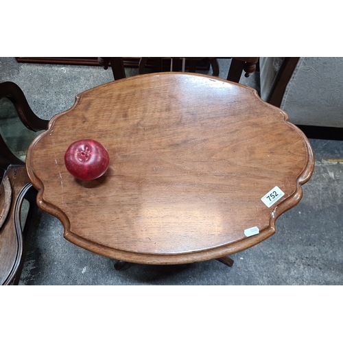 752 - Mahogany pedestal wine table features a scalloped edge top and intricately carved tripod base.