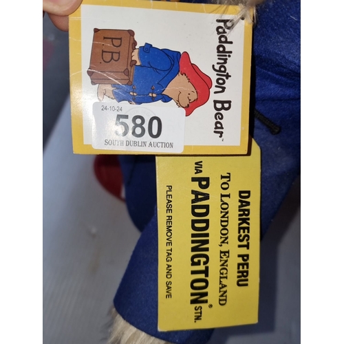 580 - Paddington Bear plush wears a blue coat and red hat, complete with original tags, referencing 