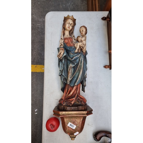 602 - A large wall mounted carved wood Madonna and Child sculpture, displaying rich colors, mounted on a d... 