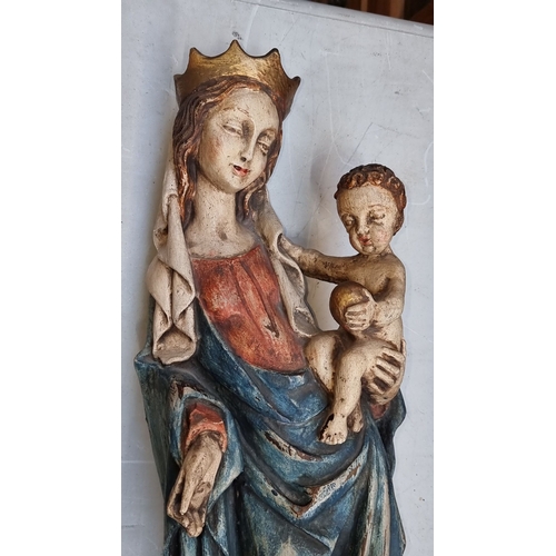 602 - A large wall mounted carved wood Madonna and Child sculpture, displaying rich colors, mounted on a d... 