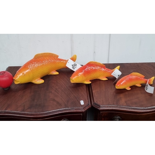 652 - Set of three decorative orange and yellow fish sculptures with mounting brackets, vibrant gradient f... 