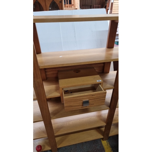 654 - Star lot : A mid century Modern oak shelving unit with six shelves and central drawer. Sleek open de... 