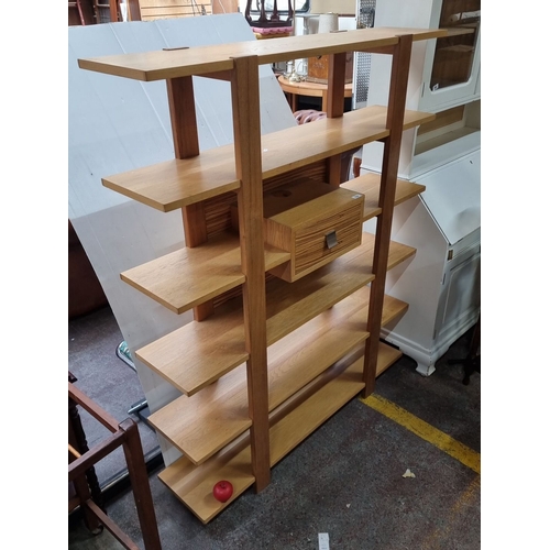 654 - Star lot : A mid century Modern oak shelving unit with six shelves and central drawer. Sleek open de... 